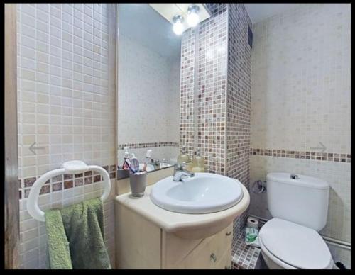 uma casa de banho com um WC branco e um lavatório. em Apartamento con piscina y cerca de la playa em Benicàssim