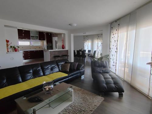 sala de estar con sofá de cuero negro y mesa en 3 bedrooms Apartman DMT, en Kaštela