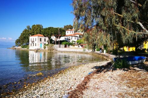 a shore with houses and a boat on the water at Eleni's Blue House by Kato Gatzea in Volos