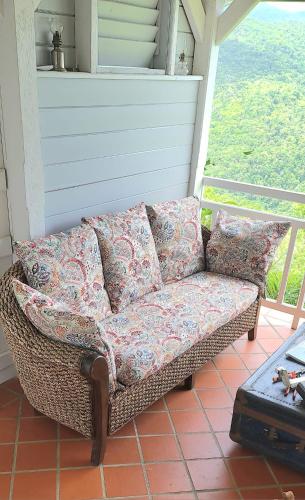 a wicker couch sitting on a screened in porch at Beausejour Guest House in Pointe-Noire