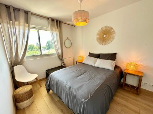 een slaapkamer met een bed, een raam en een stoel bij T2 refait à neuf – À 2 pas du bourg et des plages in Larmor-Plage