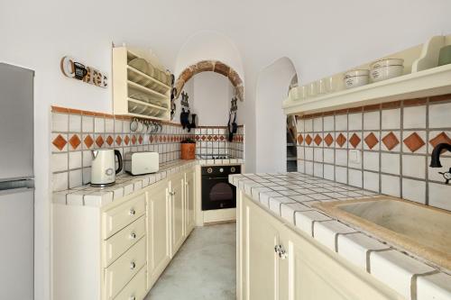 a kitchen with white cabinets and a sink at Ilivatos in Oia