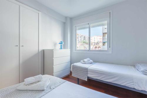 een witte slaapkamer met 2 bedden en een raam bij A&N San Gerardo 123 in Torre del Mar