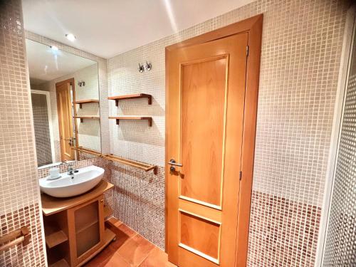 a bathroom with a sink and a wooden door at Apartamentos Boutique Terrazas in Oropesa del Mar