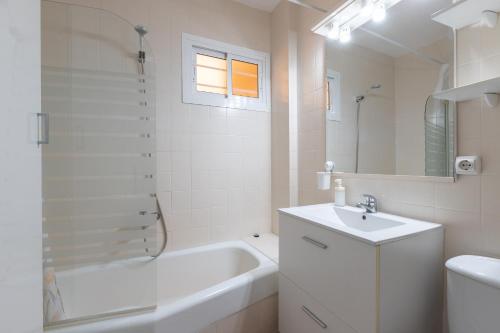 a white bathroom with a tub and a sink and a bath tubermott at Apartamento vistas a piscina in Benalmádena