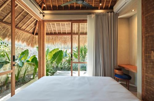a bedroom with a bed and a large window at Boni Beach Lombok Boutique Hotel in Selong Belanak