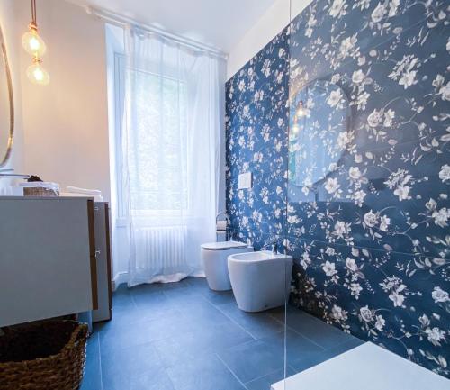 La salle de bains est pourvue de toilettes et d'un mur orné de fleurs. dans l'établissement Locanda alla Grotta, à Crone