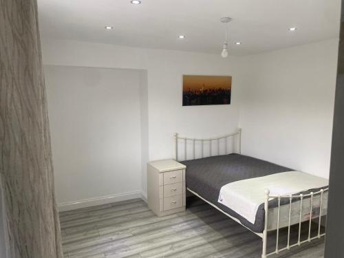 a white bedroom with a bed and a night stand at 3 Bedroom House in Loughborough in Loughborough