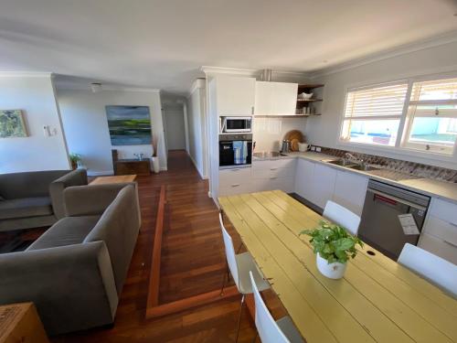 a kitchen and a living room with a wooden table at Nelson Cottage - relaxed retro, modern and original in Albany