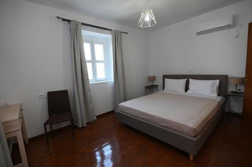 a bedroom with a bed and a desk and a window at Traditional Kos villa with swimming pool, lawn yard and bbq in Kos Town