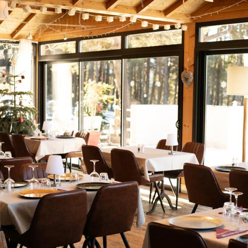 a dining room with tables and chairs and windows at Domaine de l'Adoux in Saint-Jean Montclar