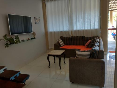 uma sala de estar com um sofá e uma televisão em Casa refúgio em Cavalcante