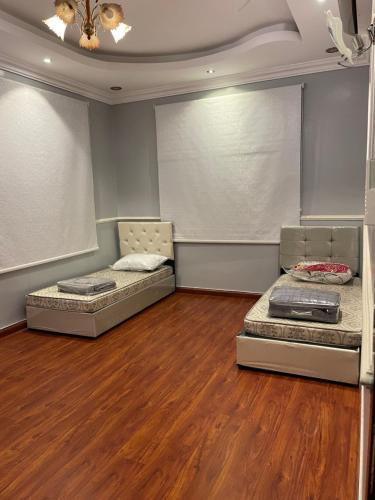 2 łóżka w pokoju z drewnianą podłogą w obiekcie غرفتين نوم ومجلس في أبها w mieście Abha
