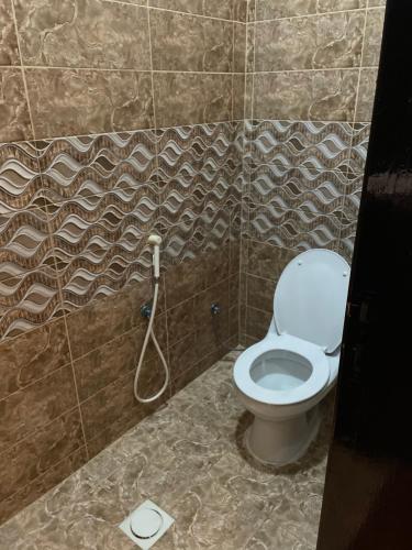 a bathroom with a toilet with a hose in it at غرفتين نوم ومجلس في أبها in Abha