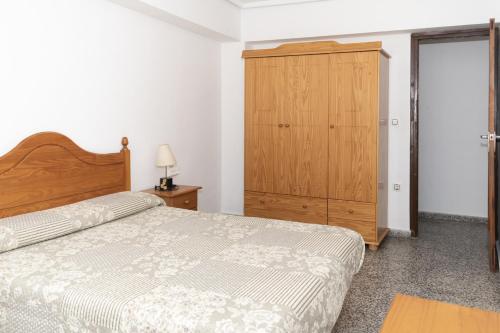 a bedroom with a bed and a wooden cabinet at Provence, 5º-17 in Cullera