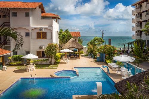 a swimming pool next to a building and the ocean at Village Paraíso in Florianópolis