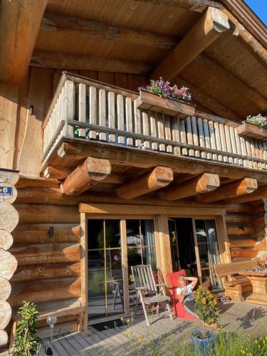 a wooden cabin with a balcony and chairs on a deck at Chalet Karin in Hochfilzen