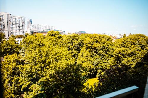 a group of trees with buildings in the background at 6th Floor Modern Apartment with French Balcony and City Views in Warsaw