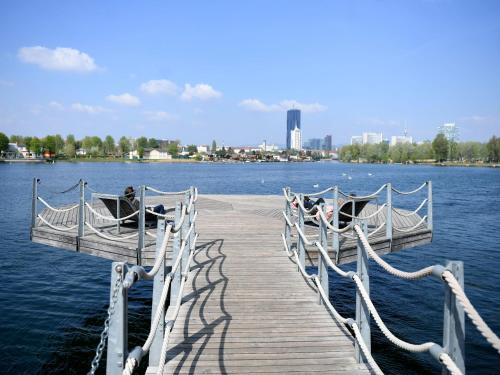 a wooden dock with two boats on the water at Ursula Rosé Collection an der Donau in Vienna