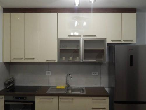 a kitchen with white cabinets and a sink and a refrigerator at Zvezda vodilja 2 in Veternik