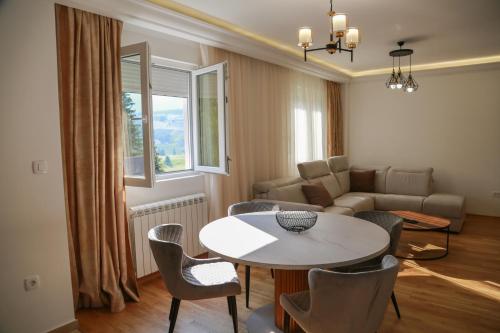 uma sala de estar com uma mesa e cadeiras e um sofá em Lakeside Serenity em Žabljak