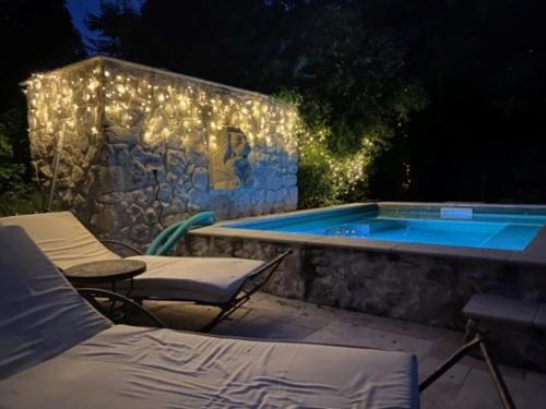 une piscine avec des chaises et un mur avec des lumières dans l'établissement Les Fontaines du Mas des Fontaines, à Montagnac