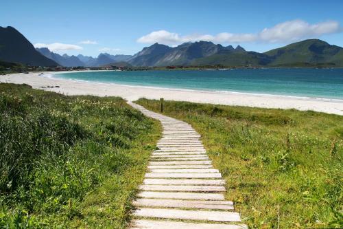 een pad naar een strand met bergen op de achtergrond bij Ramberg Gjestegård in Ramberg