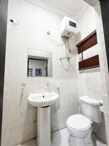 Baño blanco con aseo y lavamanos en Glides suite by Home Glides, en Lekki