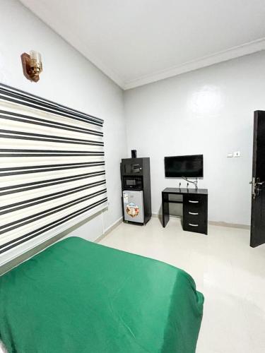 1 dormitorio con 1 cama verde y TV en Glides suite by Home Glides, en Lekki