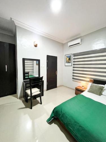 1 dormitorio con cama verde y escritorio en Glides suite by Home Glides, en Lekki
