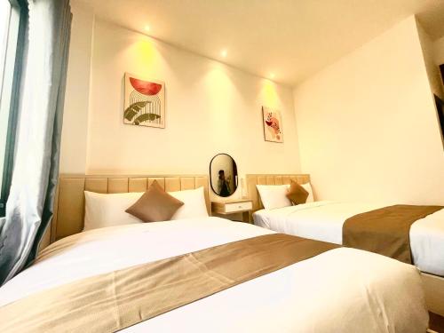 a hotel room with two beds and a window at Torino Hotel Dalat in Da Lat