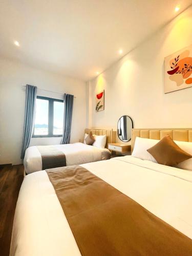 a hotel room with two beds and a mirror at Torino Hotel Dalat in Da Lat