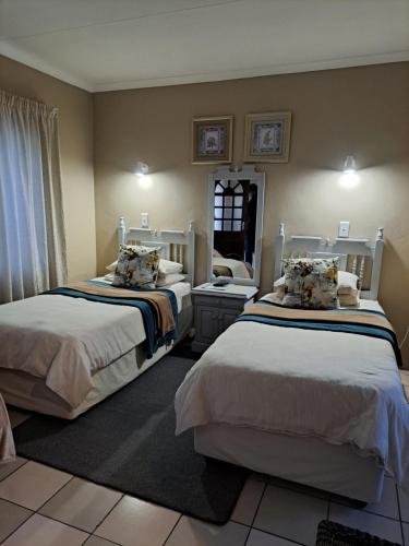 a bedroom with two beds and a mirror at At Home BB in Estcourt