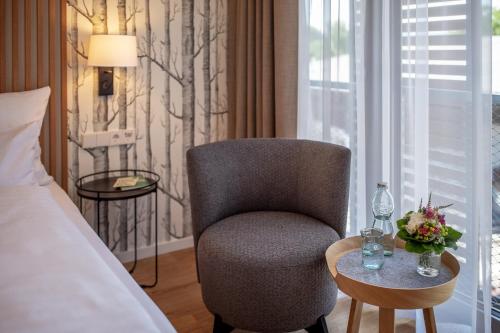 a bedroom with a chair and a table and a bed at Seehörnle Bio Hotel & Gasthaus in Gaienhofen