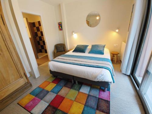 1 dormitorio con 1 cama con alfombra colorida en Le Relais des 4 Saisons - Chambres d'hôtes B&B en Baie de Somme en Saint-Valery-sur-Somme