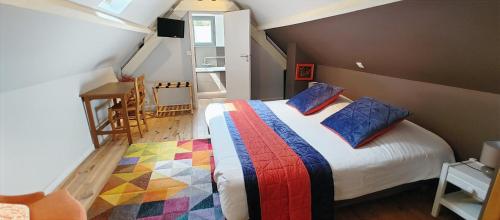 a bedroom with a bed with colorful blankets and pillows at Le Relais des 4 Saisons - Chambres d'hôtes B&B en Baie de Somme in Saint-Valery-sur-Somme