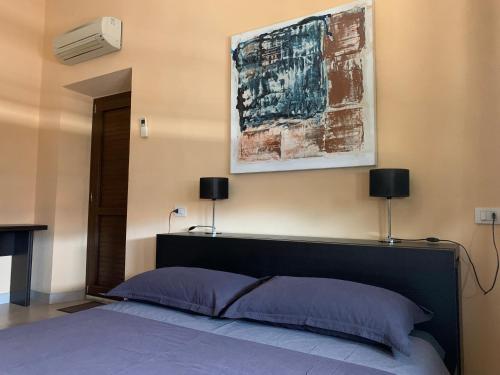 1 dormitorio con 1 cama y una pintura en la pared en Casa Cervo, en Olbia