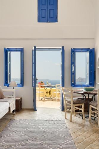 a living room with blue doors and a table and chairs at Ilivatos - Elegant Villa on the Caldera's Edge in Oia