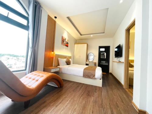 a hotel room with a bed and a chair at Torino Hotel Dalat in Da Lat