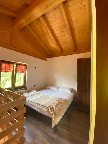 une chambre avec un lit et un plafond en bois dans l'établissement Casa Viola, à Ledro
