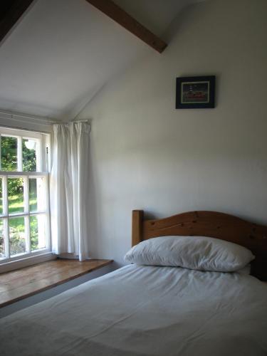 a bedroom with a bed and a window at The Old Farmhouse in Crackington Haven