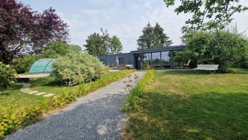 een glazen huis in een tuin met een pad bij Au Gré Des Lis 