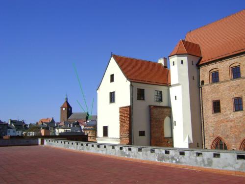 um edifício branco com um telhado vermelho ao lado de um edifício de tijolos em Pokoje Gościnne na Podzamczu em Darłowo