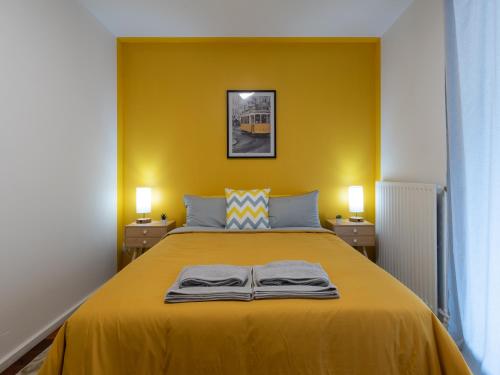 une chambre jaune avec un lit et deux lampes dans l'établissement LE PHENIX - HYPERCENTRE 16 PERSONNES GARAGE GRATUIT WiFi JARDIN BARBECUE PROCHE PARC TETE D'OR, à Villeurbanne