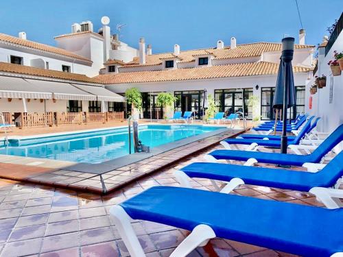 een zwembad met blauwe ligstoelen en een gebouw bij Hotel Tugasa Sierra y Cal in Olvera