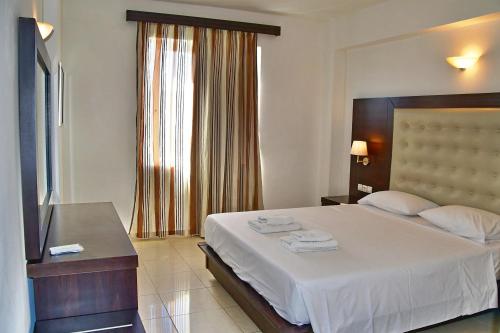 a bedroom with a large bed and a television at Castro Beach Hotel in Maleme