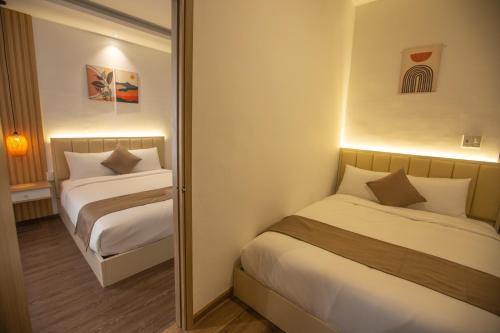 a hotel room with two beds and a mirror at Torino Hotel Dalat in Da Lat