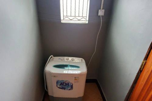 eine Waschmaschine in einer Ecke eines Zimmers mit Fenster in der Unterkunft Harukooto Suites in Fort Portal