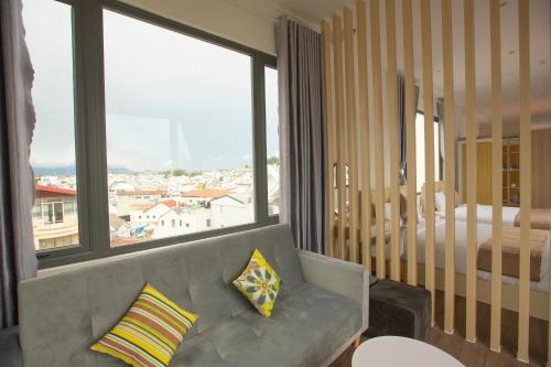 a living room with a couch and a large window at Torino Hotel Dalat in Da Lat