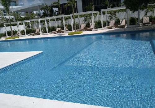 una gran piscina azul con sillas en un hotel en Apartamento VISTA AL MAR PLAYA DORMIDA 2 - por MESES POZOS COLORADOS en Santa Marta